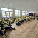 duża grupa dzieci siedzi na podłodze w odblskowych kamizelkach..jpg