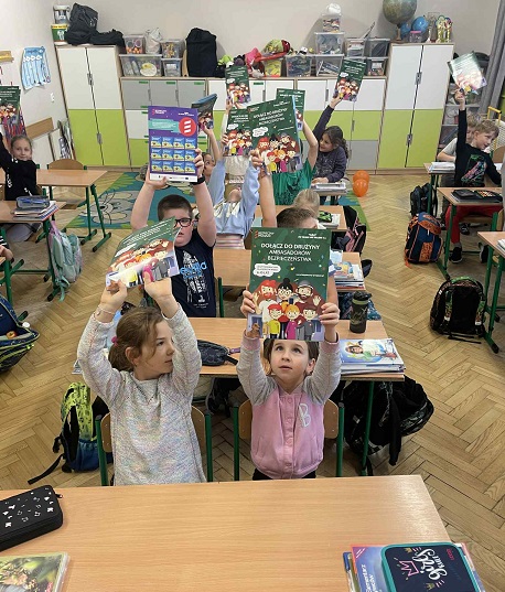 Dzieci w klasie trzymają w ekach w górze książeczki..jpg