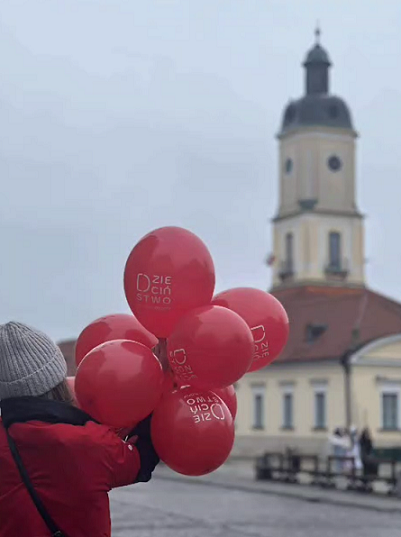 Dziecko z czerwonymi balonami na tle ratusza.PNG