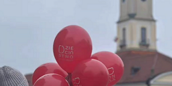 Dziecko z czerwonymi balonami na tle ratusza.PNG