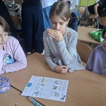 Trzy dziewczynki siedza przy stoliku z kartą pracy.jpg