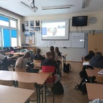 Uczniowie siedzą w ławkach klasowych i oglądają prezentację na ekranie..jpg