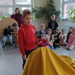 Uczeń w czerwonej bluzie stoi przy żółtym materiale.jpg