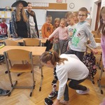 Dwie dzieczyny uśmiechają się do dzieci_ które bawia się ustawianiem butów na podłodze.jpg