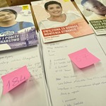 listy z plakatami przedstawiającymi osoby oraz różowymi karteczkami z numerami.jpg