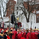 Grupa osób przebrana w czerwone peleryny z włóczniami w rękach.jpg