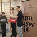 Mężczyzna wręcza dyplomy dwóm uczennicom..jpg