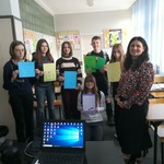 Grupa uczniów z nauczycielką pozują do zdjęcia trzymając kartki.jpg