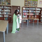 Na tle reagłów z książkami stoją dwie dziewczynki przebrane za wiosnę.jpg