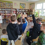 Uczniowie siedzą w bibliotece i odpowiadają na pytania.jpg