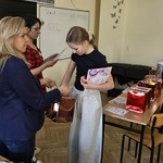 Dwie nauczycielki wręczają nagrody uczennicy w sali lekcyjnej.jpg