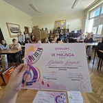 Zdjecie dyplomu za zajęcie 3 miejsca na tle uczniów siedzących w sali.jpg