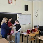 Dwie nauczycielki wręczają nagrodę uczennicy w sali szkolnej.jpg