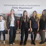 4 uczennice i chłopiec  pozują na tle baneru z napisem Ośmiu wspaniałych.jpg