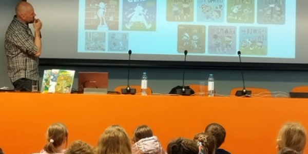Ekran z kolorowymi ksiązkami_ w tle dzieci siedzące tyłem.jpg