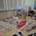 Grupa dzieci śpi na podłodze na kocach w sali lekcyjnej.jpg