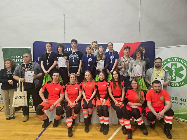 Zdjęcie grupowe uczniów z medalami i pucharami oraz z ratownikami.jpg