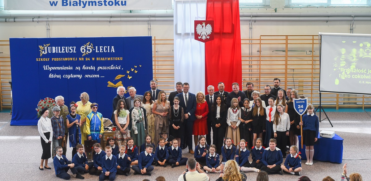 Goście oraz uczniowie przebrani w starodawne stroje szkolne pozują do wspólnego zdjęcia.jpg