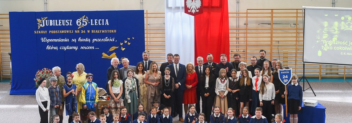 Goście oraz uczniowie przebrani w starodawne stroje szkolne pozują do wspólnego zdjęcia.jpg