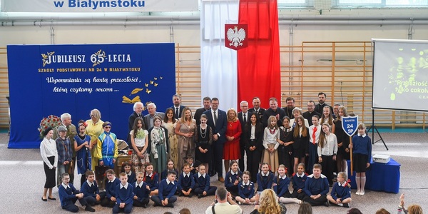 Goście oraz uczniowie przebrani w starodawne stroje szkolne pozują do wspólnego zdjęcia.jpg