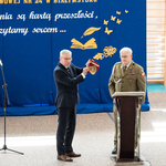 Dyrektor szkoły otrzymuje prezent od mężczyzny ubranego w mundur.jpg