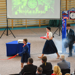 uczniowie przebrani w fartuszki i stare stroje występują na scenie.jpg