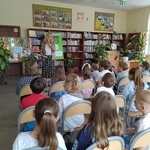 Nauczycielka czyta uczniom siedzącym w bibliotece.jpg