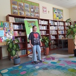 Uczennica stoi w bibliotece na kolorowym dywanie..jpg