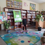 uczeń  recytuje wiersz stojąc na kolorowym dywanie w bibliotece.jpg