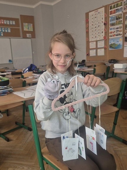 Dziewczynka trzyma wieszak z karteczkami_ w drugiej ręce ma pacynkę.jpg