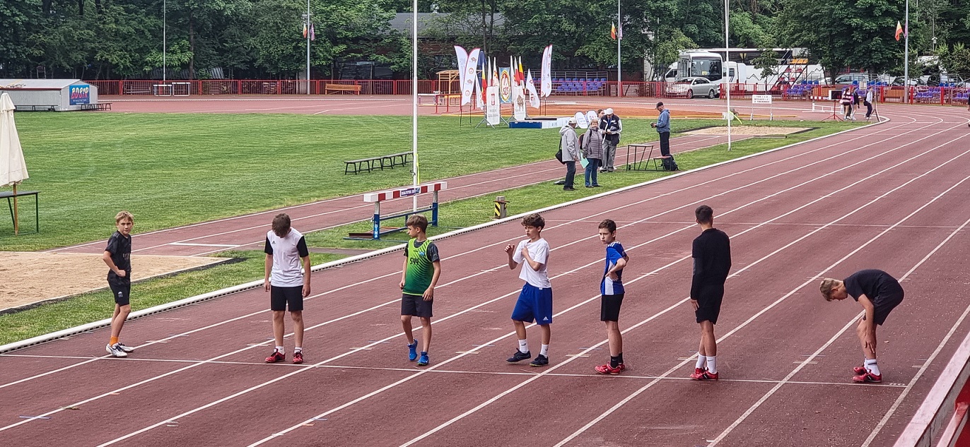 chłopcy stoją na korcie sportowym  i szykują się do startu.jpg