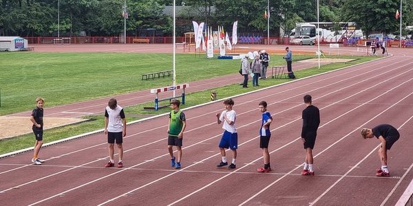 chłopcy stoją na korcie sportowym  i szykują się do startu.jpg
