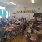 Nauczycielka czyta dzieciom siedzącym w ławkach w klasie..jpg