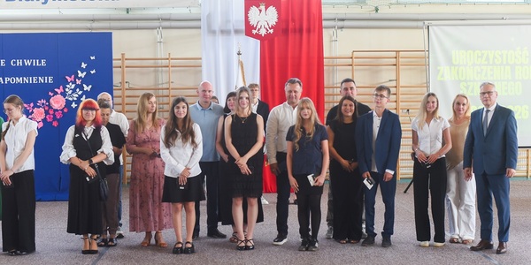 Grupa osób stoi na hali gimnastycznej_ w tle flaga Polski.jpg