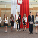4 dziewczyny i 2 chłopaków elegancko ubrani pozują do zdjęcia ze sztandarem na tle flagi Polski.jpg