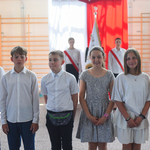 Grupa uczennic i uczniów elegancko ubranych pozuje do zdjęcia  na tle flagi Polski..jpg