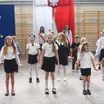 Grupa dzieci tańczy_ w  tle napis Witaj szkoło i flaga polskia z godłem..jpg