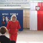 Pani dyrektor w czewonej sukience na tle flagi Polski.jpg