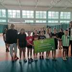 Grupa dzieci w sporotwych strojach razem z 2 nauczycieli pozuje do zdjęcia na sali sportowej.jpg