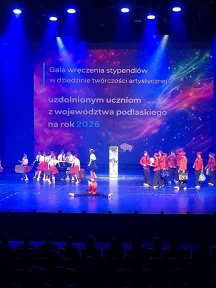 Grupa artystów na scenie z niebieskim światłem.jpg