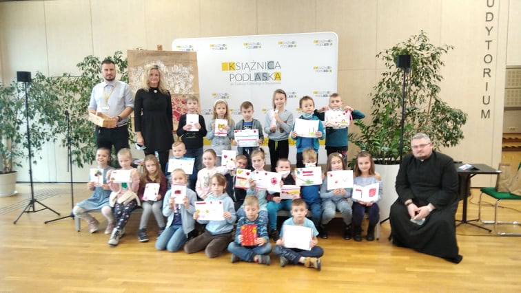 Uczniowie wraz z opiekunami trzymający laurki w Książnicy Podlaskiej.