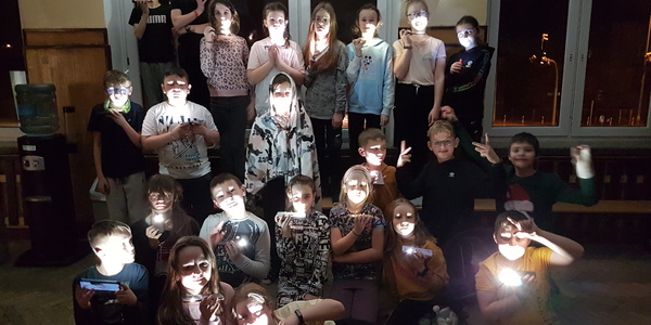 Uczniowie oświetlający swoje twarze komórkami