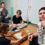 Uczniowie jedzący pizzę podczas wieczoru filmowego.
