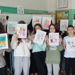 Uczniowie z kolorowymi rysunkami.