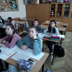 Uczniowie siedzacy w ławkach.