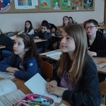 Uczniowie siedzacy w ławkach.