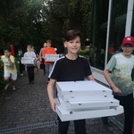 Uczniowie niosący pizzę.