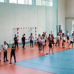 Uczniowie ćwiczą na niebiesko-pomarańczowej hali sportowej.