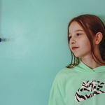 Zdjęcie dziewczyny z profilu na tle zielonej ściany.