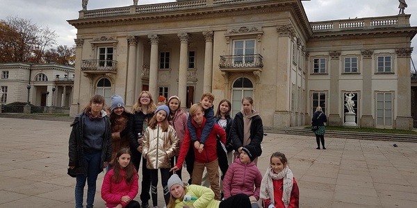 Uczniowie stoją na tle Pałacu na Wodzie w Łazienkach Królewskich.